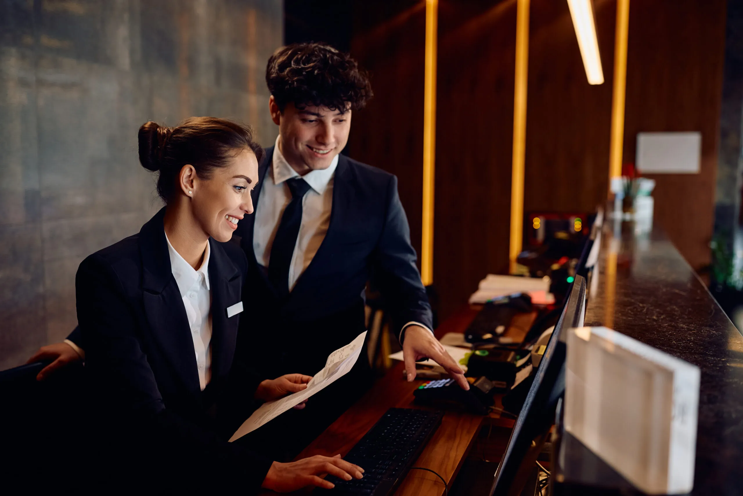 Two hotel front desk staff reviewing a reservation together